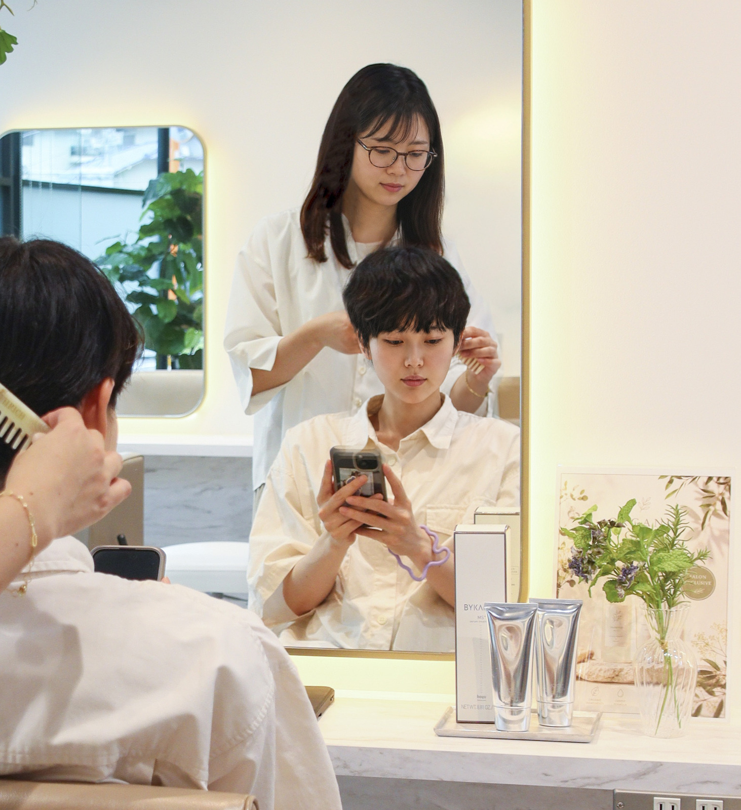美容室の鏡の前でスマートフォンを見ながら過ごすお客様