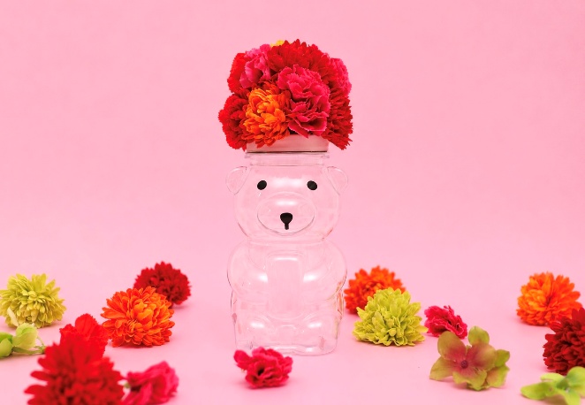 赤とオレンジの花でアフロヘアを表現したベアのフラワーアレンジ