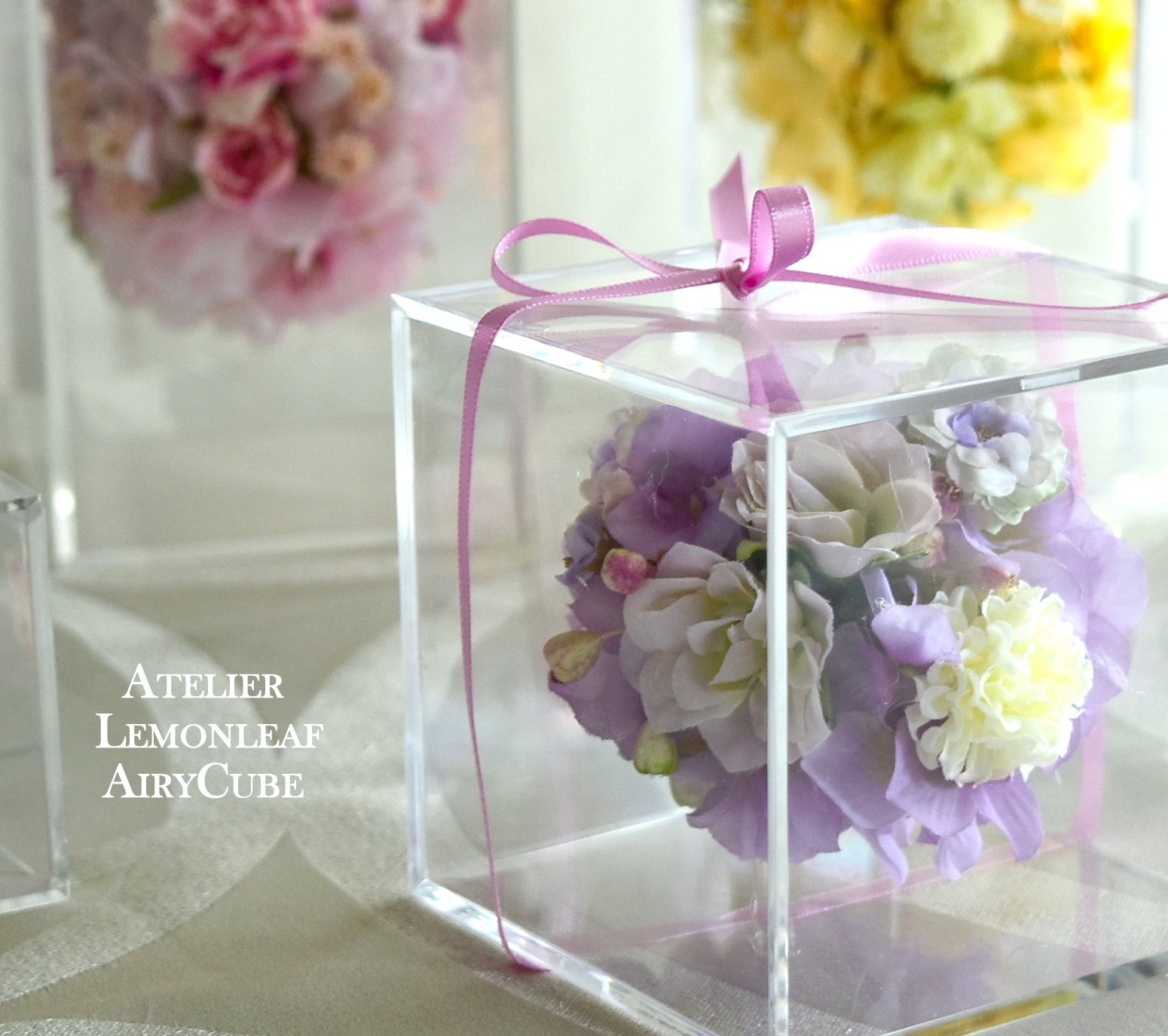 アトリエレモンリーフのエアリーキューブ。透明なキューブに浮かぶパープル系の花のアレンジ