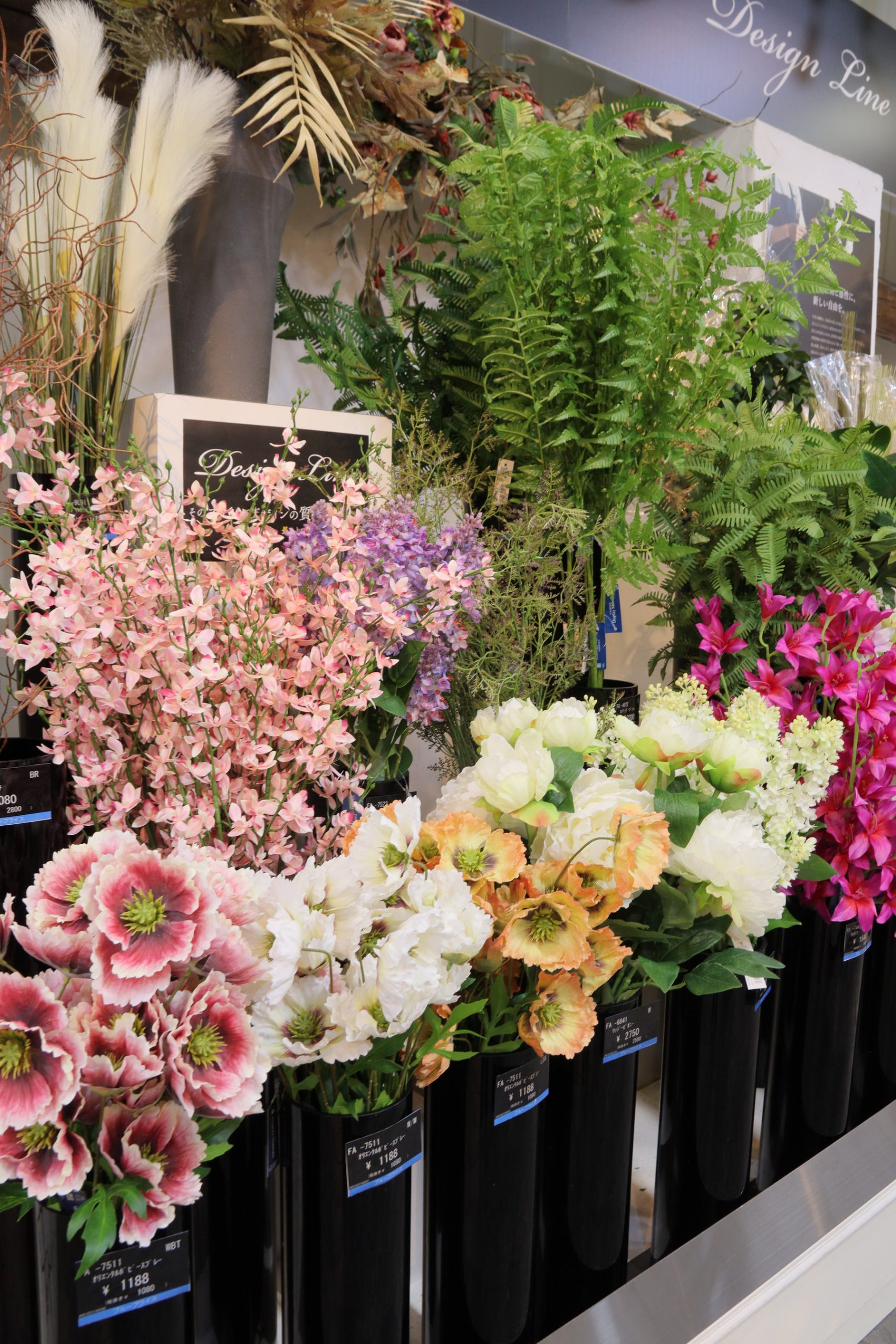 ピンクやグリーンの花材が並ぶ売場