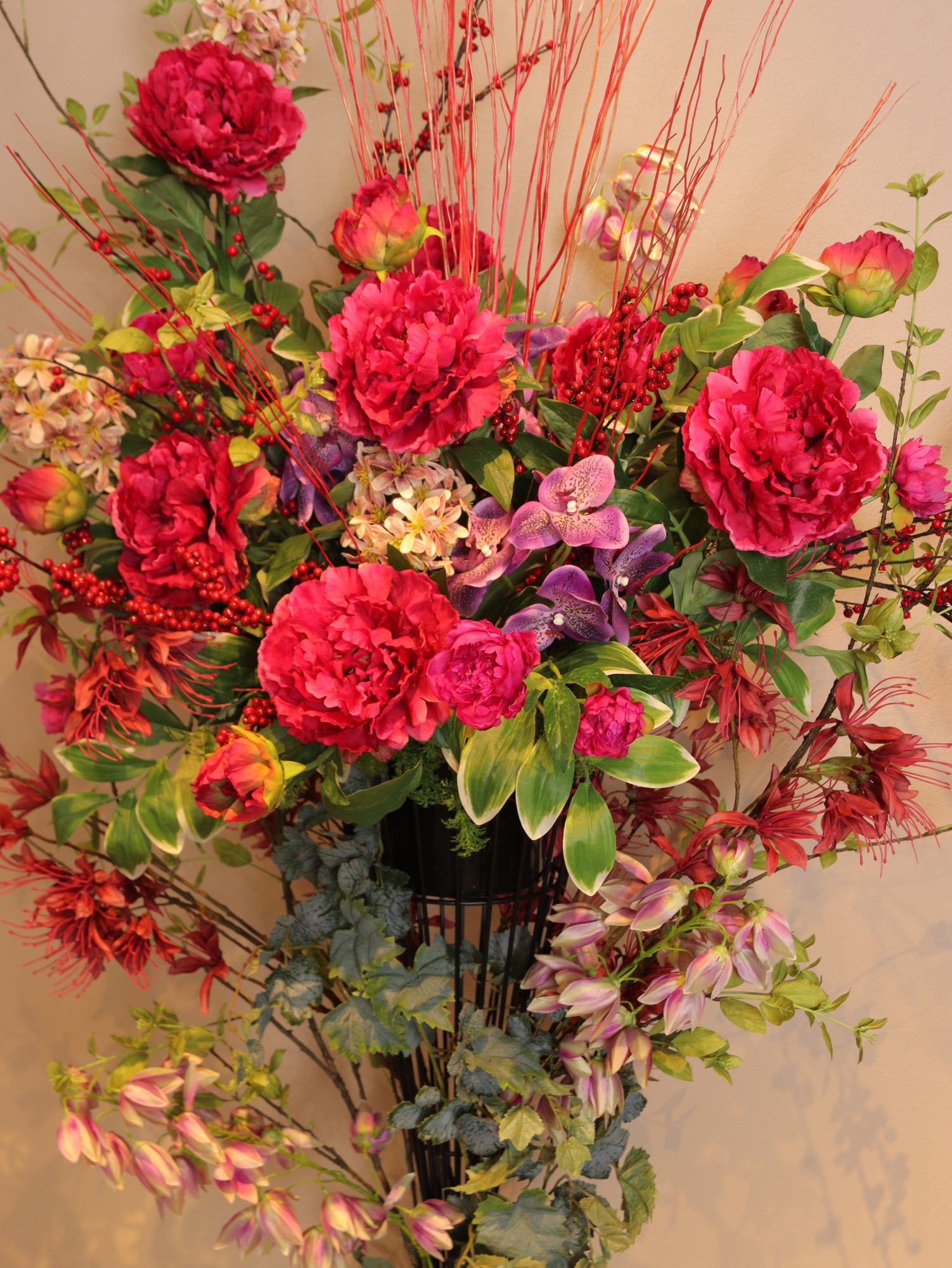 赤紫の花と枝ものを組み合わせたスタンドフラワー